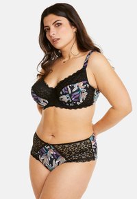 Soutien-gorge et culotte assortis avec dentelle noire, mettant en avant un imprimé floral coloré sur fond sombre. Comprend des bords festonnés et des accents en dentelle transparente.