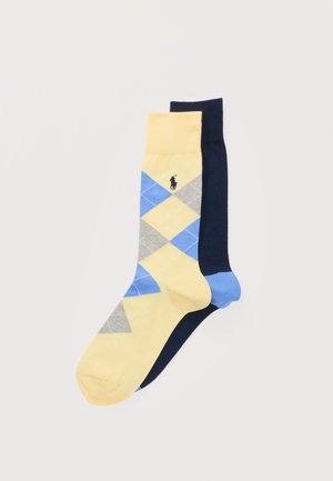 Een paar sokken halverwege de kuit, de ene geel met een ruitpatroon in blauw en grijs en een klein zwart logo, de andere effen donkerblauw met een blauwe hiel.