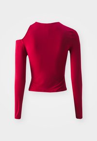 Red long-sleeve top made of smooth fabric, featuring a cold shoulder design and fitted silhouette. Cropped length with a crew neckline.
