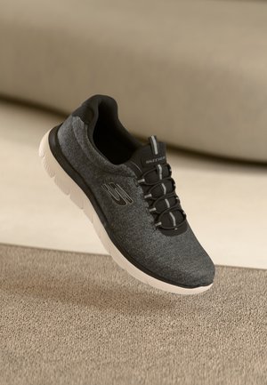 Black fabric sneaker with gray accents, textured upper, rounded toe, pull tab, and white lightweight sole, featuring black laces.