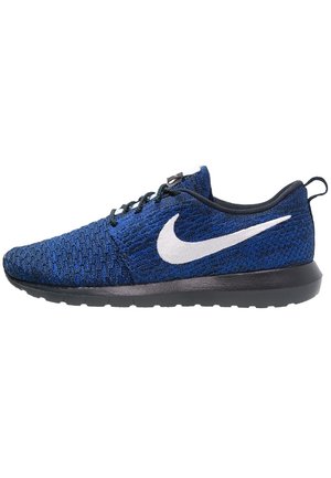 Sininen Nike juoksukenkä mustalla pohjalla, valkoisella Swoosh-logolla, mustilla nauhoilla ja teksturoidulla neulotulla päällisellä, nähtynä sivulta.