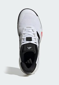 Bela športna obutev z zgornjim delom iz zračne mrežice, črnimi poudarki in rdečimi detajli na podplatu. Ima zavezovanje z vezalkami in oblazinjeni jezik.