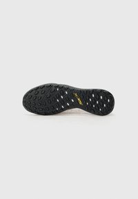 Semelle extérieure en caoutchouc noir texturé avec des rainures multidirectionnelles, dotée d'un design minimaliste et d'un logo "SKY" en jaune bien visible.