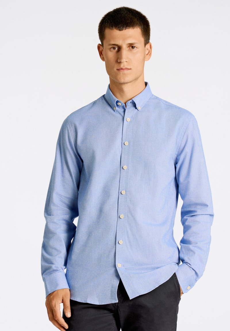 Vaaleansininen napitettava paita klassisella muotoilulla, jossa on kaulus, pitkät hihat ja rento istuvuus, sekä eriväriset napit.