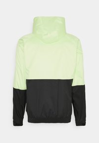 Ljusgrön och svart vindjacka med huva, med en färgblockdesign och elastiska ärmslut och nederkant. Slät, glänsande material.