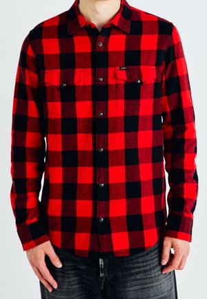 Punainen ja musta ruudullinen flanellipaita nappikiinnityksellä, kahdella rintataskulla, pitkät hihat ja teksturoitu kangas. Vakiomuotoinen kaulusetti.