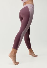 Leginsy w głębokim mauve i jasnym fioletowym z wysokim pasem, wykonane z gładkiego, elastycznego materiału z kontrastującymi bocznymi panelami.