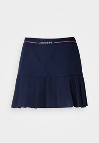 Tmavě modrá plisovaná sukně s elastickým pasem, která má bílo-růžové logo Lacoste. Vyrobena z hladkého, lehkého materiálu.