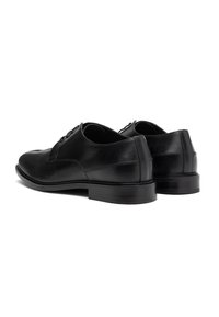 Scarpe eleganti in pelle nera con superficie liscia, punta arrotondata e tre occhielli per i lacci. Presentano un tacco basso e robusto.