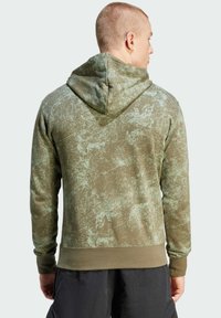 Olivgrön hoodie med ett texturerat mönster, som har en huva och ribbade muddar. Mjukt tyg med en subtil gradering och avslappnad passform.