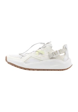 White athletic sneaker with mesh upper, adjustable elastic laces, heel strap, and brown textured sole, shown in side profile.