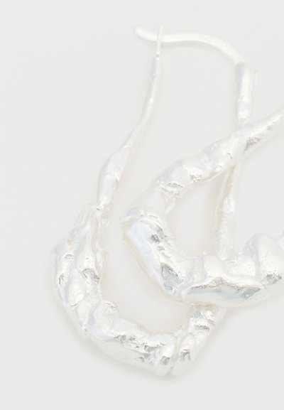 Boucles d'oreilles créoles torsadées ton argent avec une finition texturée, présentant des formes irrégulières et des surfaces lisses et réfléchissantes.