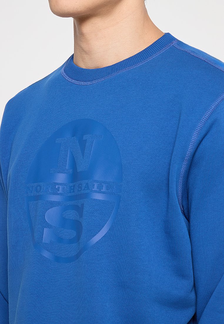 Felpa di cotone blu con scollo rotondo, caratterizzata da un design del logo in rilievo di una tonalità blu più scura sulla parte frontale. Texture liscia, cuciture visibili.