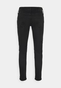 Černé džíny s úzkým střihem, které mají klasický design se šesti kapsami a jemné švy na zadních kapsách.