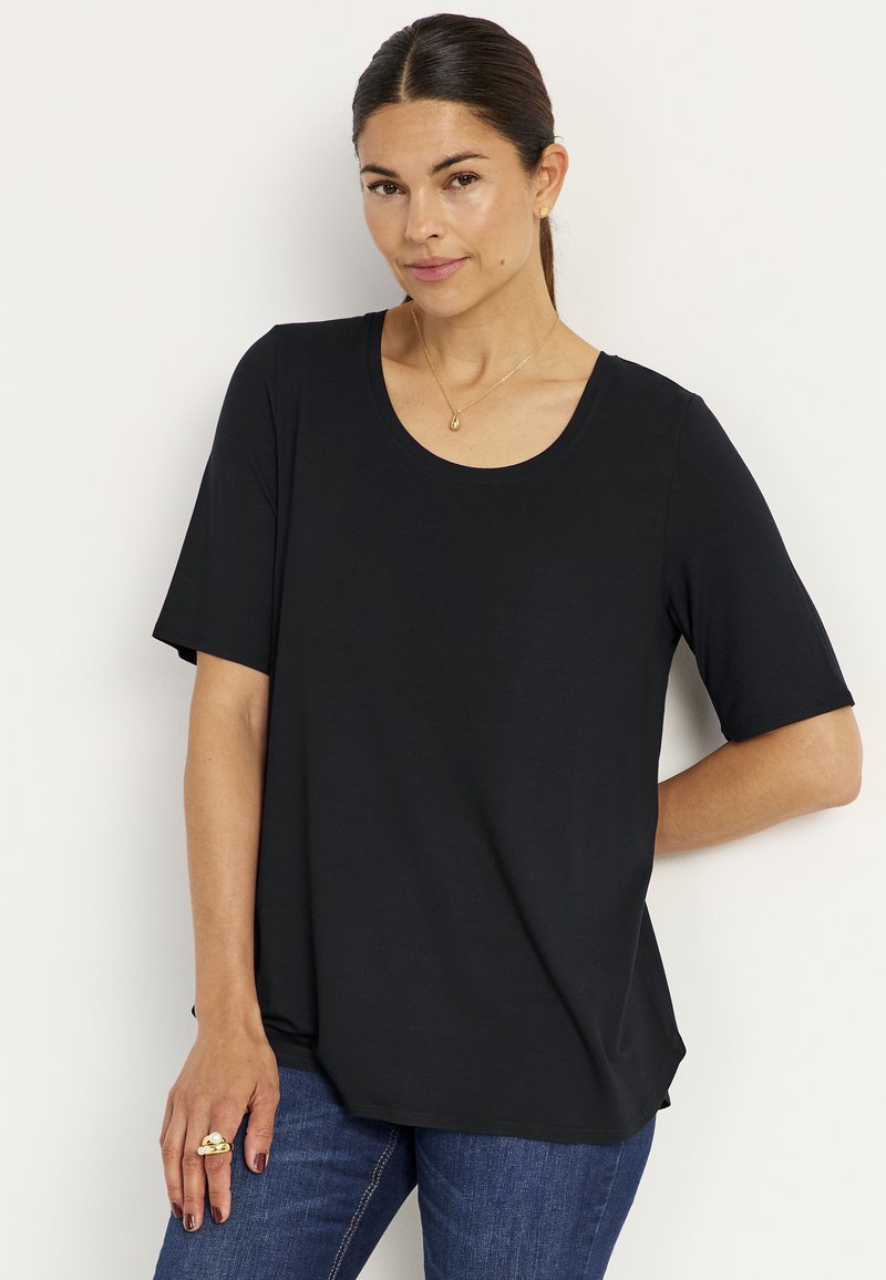 Svart kortärmad T-shirt med rund halsringning, tillverkad av slät tyg. Lite löst passform, parat med blå denimjeans.