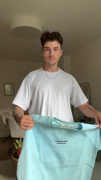 Light blue sweatshirt with a rounded neckline, ribbed cuffs, and "GRANTED GOODS" printed on front. Fabric appears soft and textured.