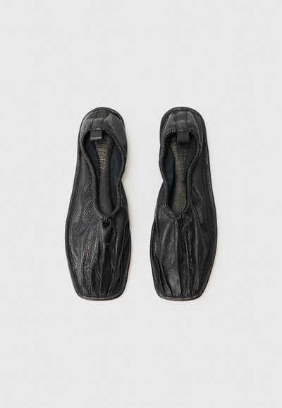 Fekete bőr slip-on cipők, texturált felülettel, puha bélés belül, és ráncolt dizájnnal a nyílásnál. Lapos talp, díszítés nélkül.