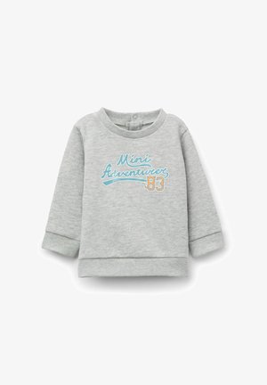 Sweatshirt gris en tissu doux, avec des manches longues, des poignets côtelés et un design imprimé avec "Mini Aventuriers 83" en bleu et orange.