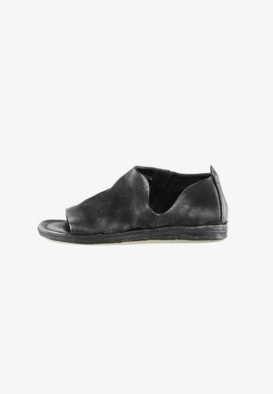 Chaussure mule en cuir noir à bout ouvert avec dessus texturé et semelle plate basse, découpe latérale pour un accès facile au pied.