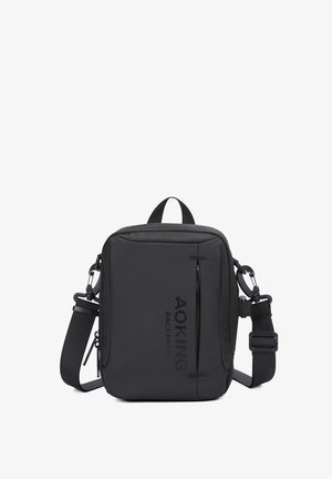 Schwarze Umhängetasche aus strapazierfähigem Gewebe, mit einer vorderen Reißverschlusstasche, verstellbarem Gurt und Markenaufdruck auf der Vorderseite.