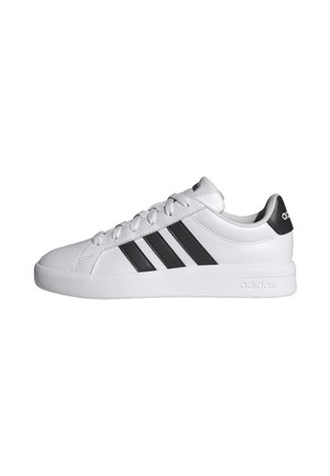 Sneaker Adidas bianca con tre strisce nere sul lato, lacci bianchi e linguetta nera sul tallone con il logo Adidas.