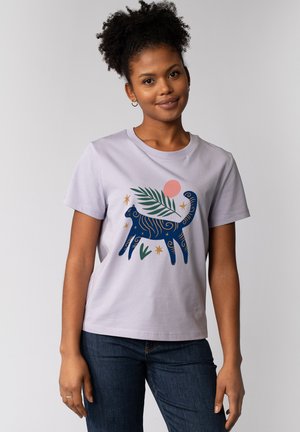 Light purple T-shirt featuring a blue abstract cat graphic with green leaves and a pink sun. Simple design, soft cotton material.