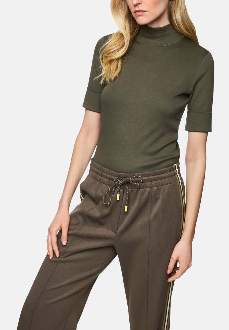 Olive green short-sleeve turtleneck paired with brown athletic pants featuring a drawstring waist and yellow side stripes. Smooth texture.