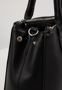 Borsa a tracolla in pelle nera con finitura testurizzata, hardware in argento, manici doppi e chiusura con zip in alto.