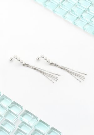 Silberne Tropf-Ohrstecker mit sphärischen Perlenakzenten und mehreren zarten Ketten, präsentiert auf einem weißen Hintergrund mit Glasblöcken.