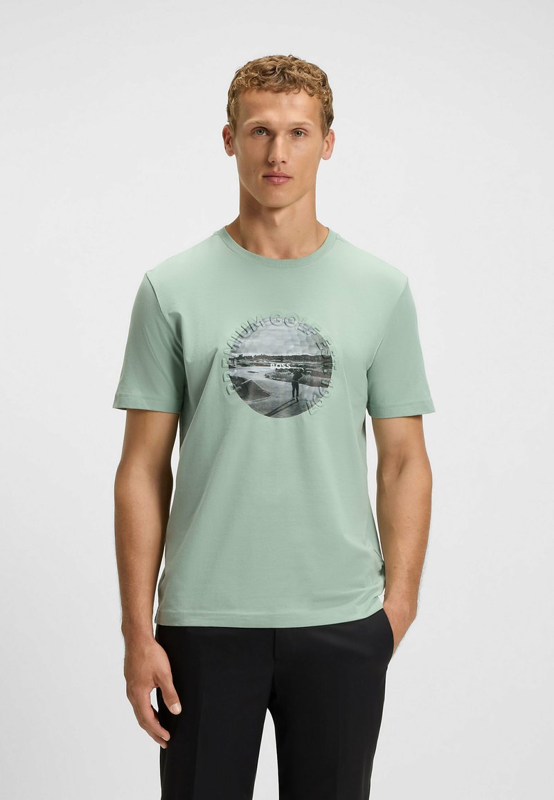 Light green cotton t-shirt featuring a circular graphic print at the center, depicting a black-and-white landscape. Short sleeves and crew neck.