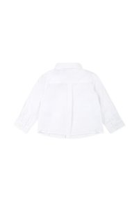 Camicia bianca a maniche lunghe in cotone, con colletto, polsini a bottoni e una piega centrale sul retro per un maggior volume.