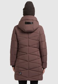 Müüdud mauve puffer-jakk, millel on tikitud rombimuster, kapuuts ja logoaktsent seljal. Omab pikki varrukaid ja sirget äärt.