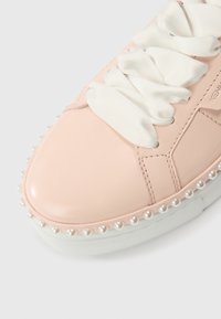 Ροζ δερμάτινο αθλητικό παπούτσι με στρογγυλεμένη μύτη, λευκές σατέν κορδέλες και διακοσμητική πέρλα κατά μήκος της σόλας. Υφή στη λαστιχένια εξωτερική σόλα.