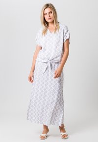 Lichtgrijze maxi-jurk met een geometrisch patroon, korte mouwen, V-hals en een strikceintuur. De stof lijkt glad en lichtgewicht te zijn.