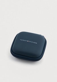 Granatowe etui na zamek błyskawiczny, o gładkiej fakturze i logo "TOMMY HILFIGER" w kolorze białym. Kompaktowy, kwadratowy kształt.