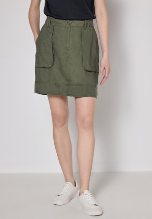 Jupe en lin vert olive, longueur genoux, avec deux grandes poches avant, une fermeture à boutons et des détails de couture visibles.