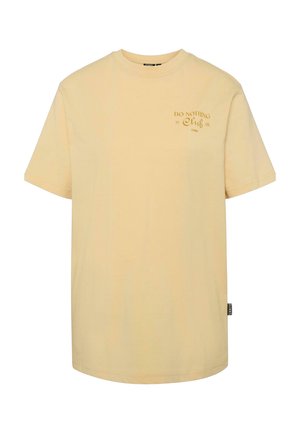Dzeltena kokvilnas T-krekls ar īsām piedurknēm un apaļu kakla izgriezumu. Priekšpusē ir izdrukāts "DO NOTHING Club" teksts kontrastējošā krāsā.