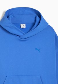 Felpa blu brillante con una grande tasca frontale e un piccolo logo Puma ricamato sul petto, caratterizzata da un collo rilassato.
