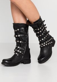 Czarne skórzane botki za kostkę z lekko spiczastym noskiem, ozdobione poziomymi paskami i metalowymi ćwiekami, z niskim, platformowym obcasem.