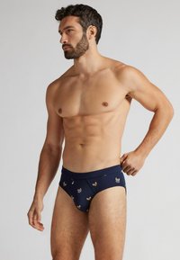 Námořnické modré bavlněné boxerky s vzorovaným designem, na kterém jsou malá psí plemena, elastický pas a přiléhavý střih. Měkká textura a těsné pohodlí.