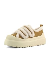 Sneaker met dikke crèmekleurige zool, bruine suède bovenkant, en pluche witte vachtbanden en voering, schuin naar rechts op witte achtergrond.