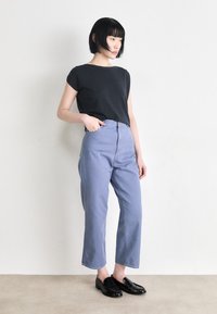 Top preto de manga curta, calças de cintura alta em azul claro e mocassins pretos. Ajuste Slim, textura suave e design de perna reta.
