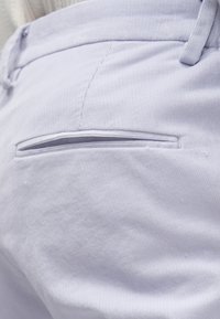 Vaaleansiniset mannapintaiset housut, joissa on takatasku ja ohut, huomaamaton sauma. Materiaali on pehmeää ja ribbattua, esitellen tyylikkään designin.