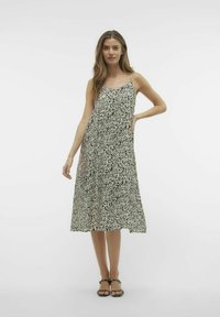 Czarna i biała midi sukienka w wzory z cienkimi ramiączkami, w kształcie litery A, wykonana z lekkiego materiału, charakteryzująca się zwiewnym fasonem i bocznymi kieszeniami.