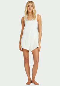 White sleeveless romper with a ribbed texture, featuring a relaxed fit, short hemline, and a slight scoop neckline.