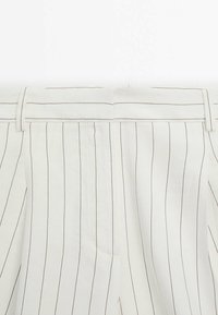 Witte broek met verticale bruine strepen, met een gladde textuur en een platte tailleband. De stof lijkt lichtgewicht en ademend te zijn.