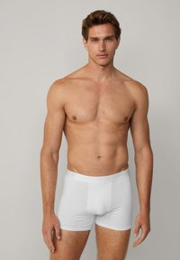 Shorts en coton blanc avec une ceinture élastique douce. Les shorts présentent une texture lisse et un design ajusté qui épousera le corps.