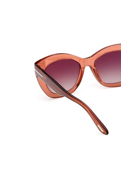 Gafas de sol estilo cat-eye con montura transparente ámbar, lentes graduales en púrpura y patillas taperadas con sutiles acentos metálicos.