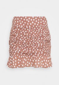 Raffinerad minikjol i terrakottafarve med ett mönster av vita prickar. Har en utsvängd fåll och ett mjukt, elastiskt tyg.