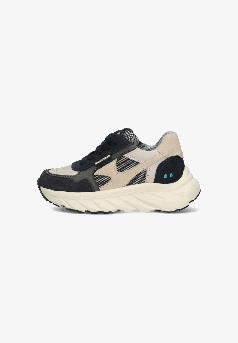 Sneaker featuring a mesh upper in beige and black, with suede accents, a thick white midsole, and green dot details on the heel.
